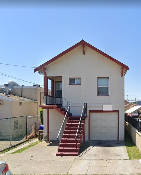 a white house with red stairs and a balcony
