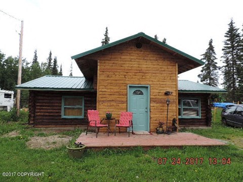 a wooden cabin with two chairs and a table on the porch