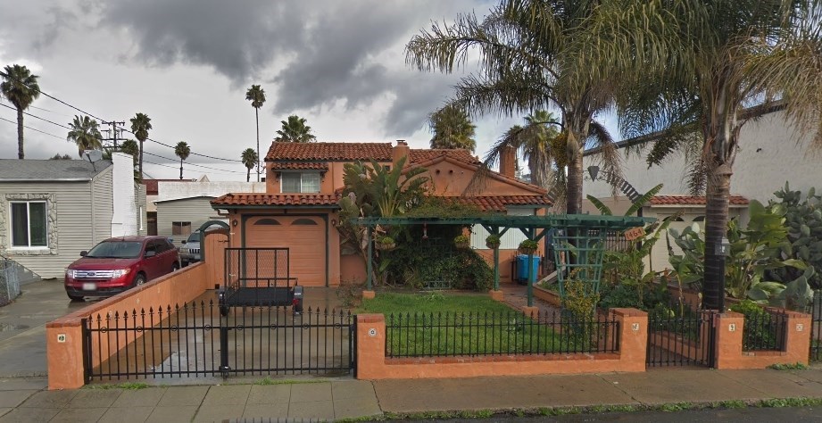 A house with a red roof and a black gate.
