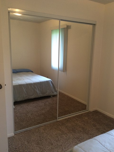 A bedroom with a bed and a mirror.