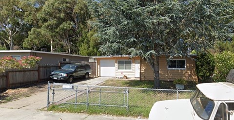 A white car is parked in front of a house.