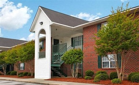 a red brick building with a porch and a staircase