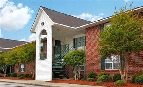 a red brick building with a porch and a staircase