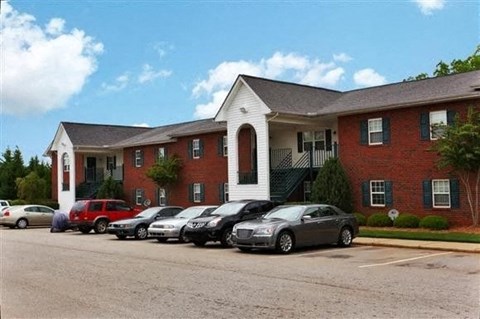 A parking lot with cars and a red brick building with a white trim.