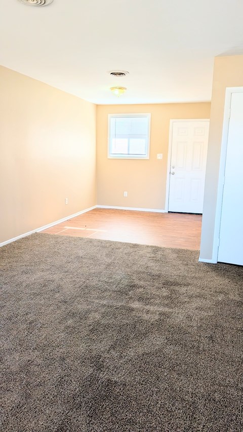 A room with a carpeted floor and a white door.