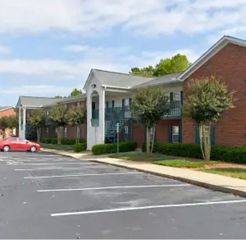 A red car is parked on the left side of a parking lot.