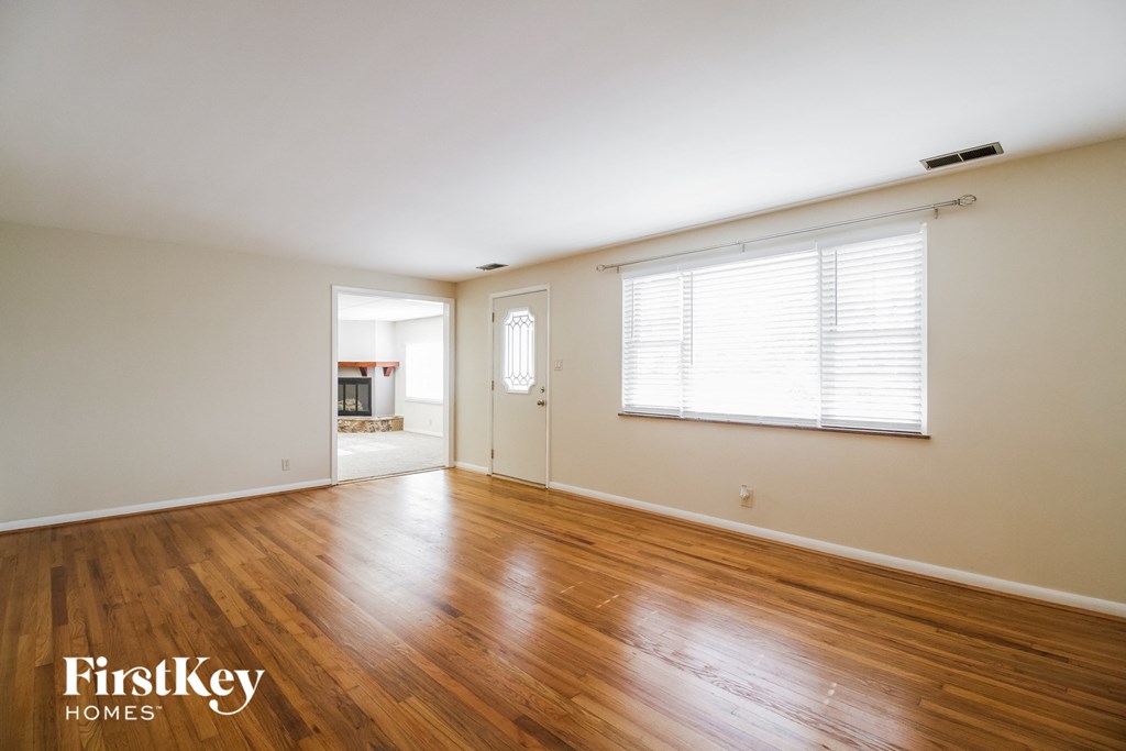 A room with wooden floors and a window with blinds.