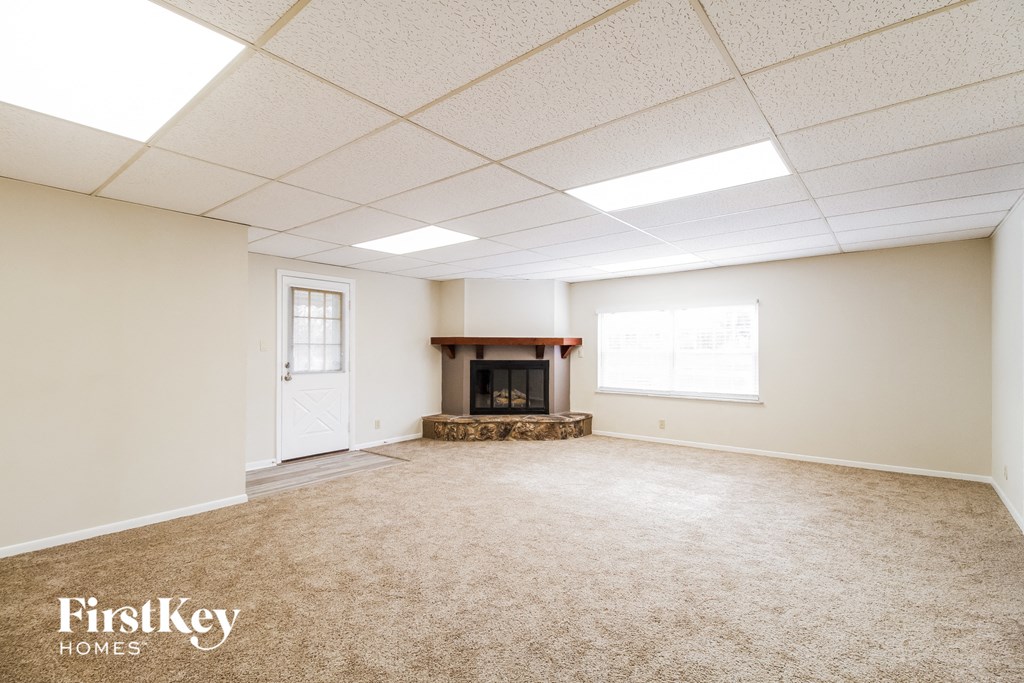 A spacious room with a fireplace and a carpeted floor.