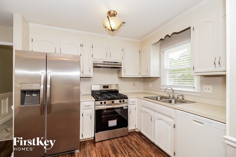 A kitchen with a stainless steel refrigerator and wooden floors.