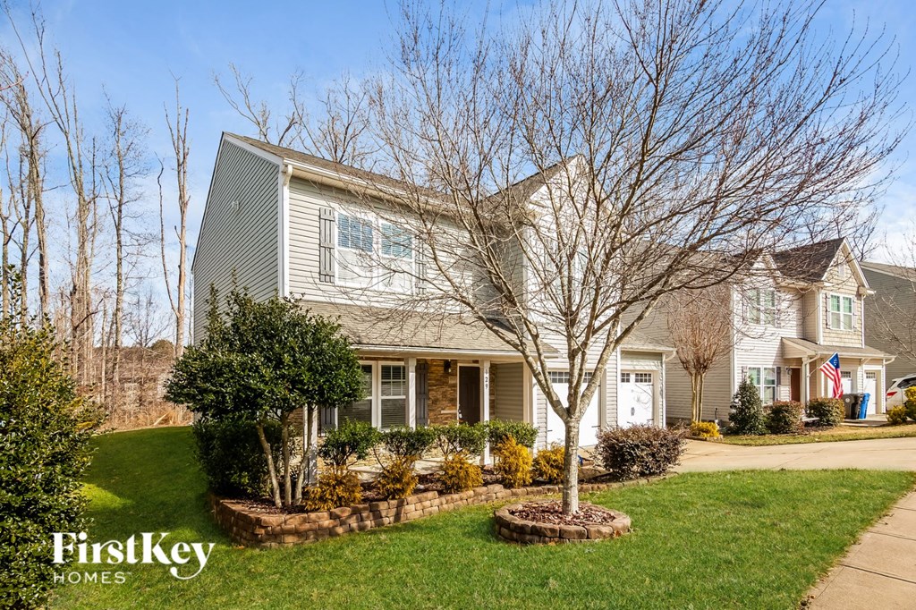 A house with a grey roof and a tree in front of it.