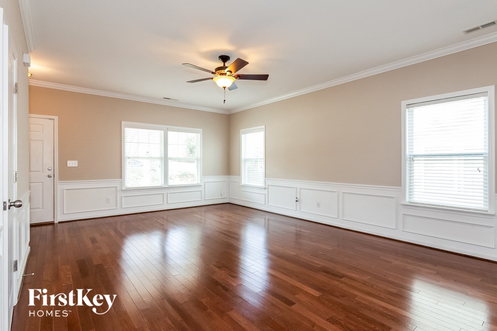 A spacious room with wooden floors and a ceiling fan.