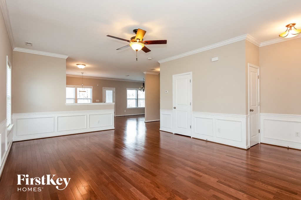 A spacious room with wooden floors and a ceiling fan.