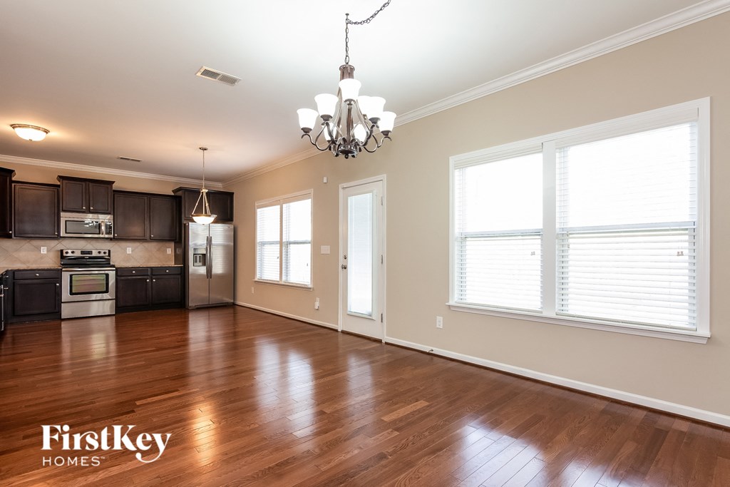 A well-lit kitchen and living room with wooden floors and a chandelier.