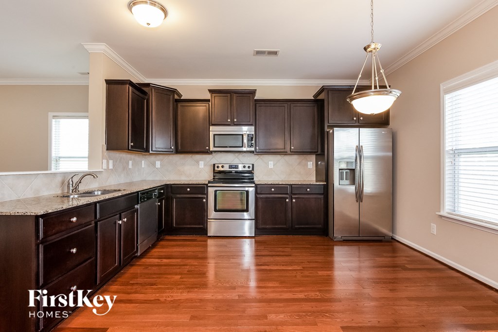 A kitchen with dark brown cabinets and a wooden floor.