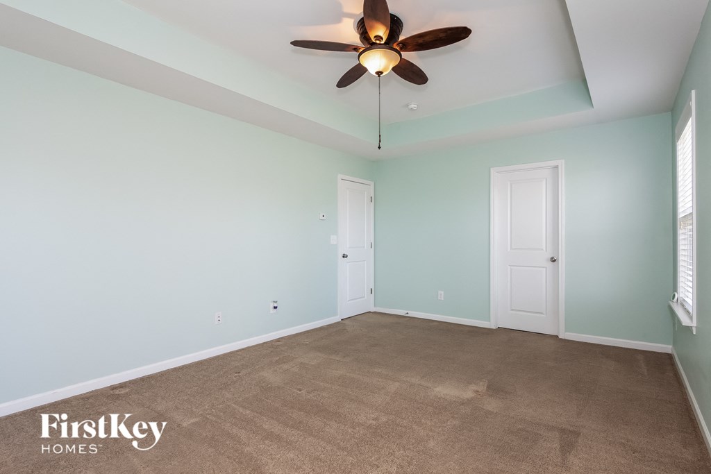 A room with a ceiling fan and two doors.