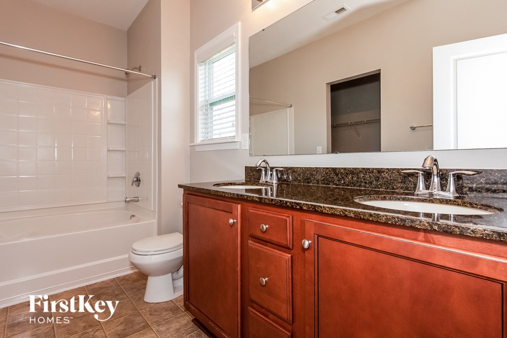 A bathroom with a wooden vanity and a white toilet.
