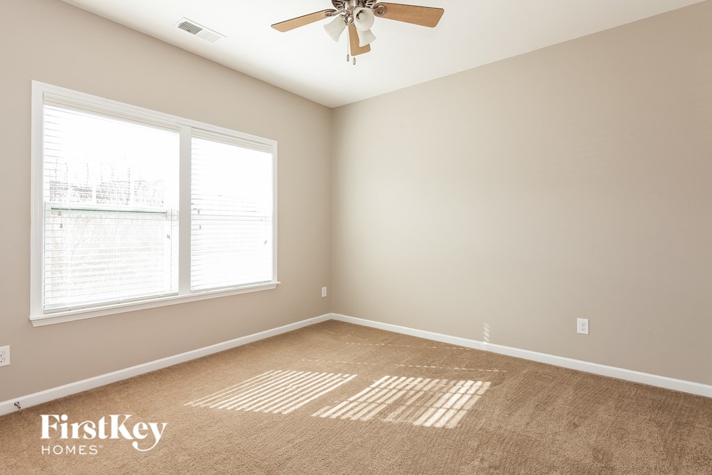 A room with a carpeted floor and a ceiling fan.