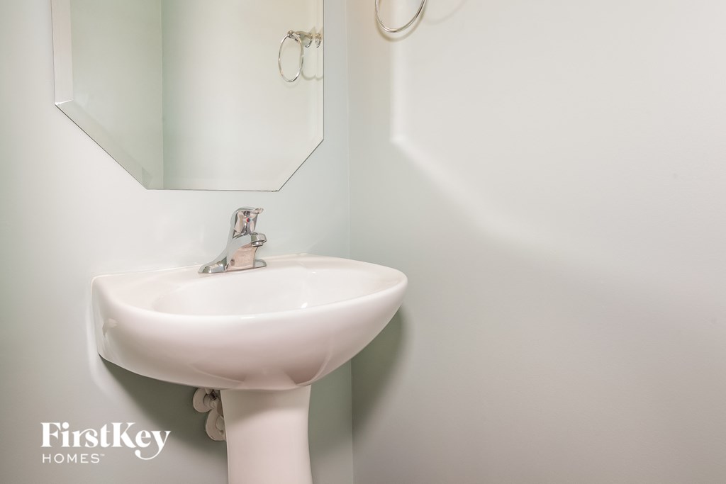 A white sink in a bathroom with a mirror above it.