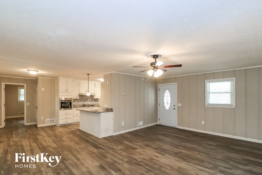 the living room and kitchen of an empty house with a ceiling fan