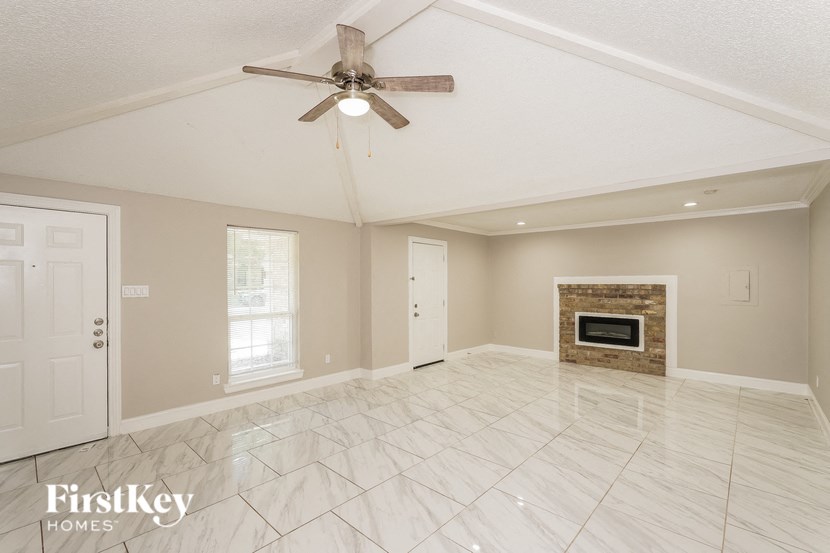 an empty living room with a ceiling fan and a fireplace