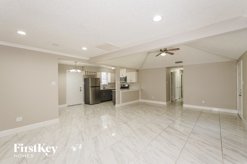 an empty living room and kitchen with a ceiling fan