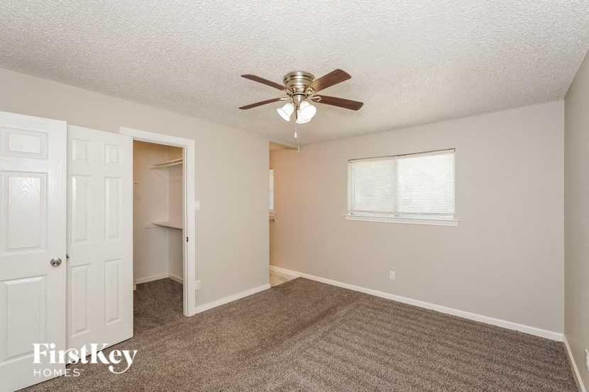 a bedroom with a ceiling fan and a door to a closet
