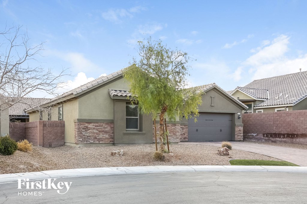 a house with a garage and a tree in front of it