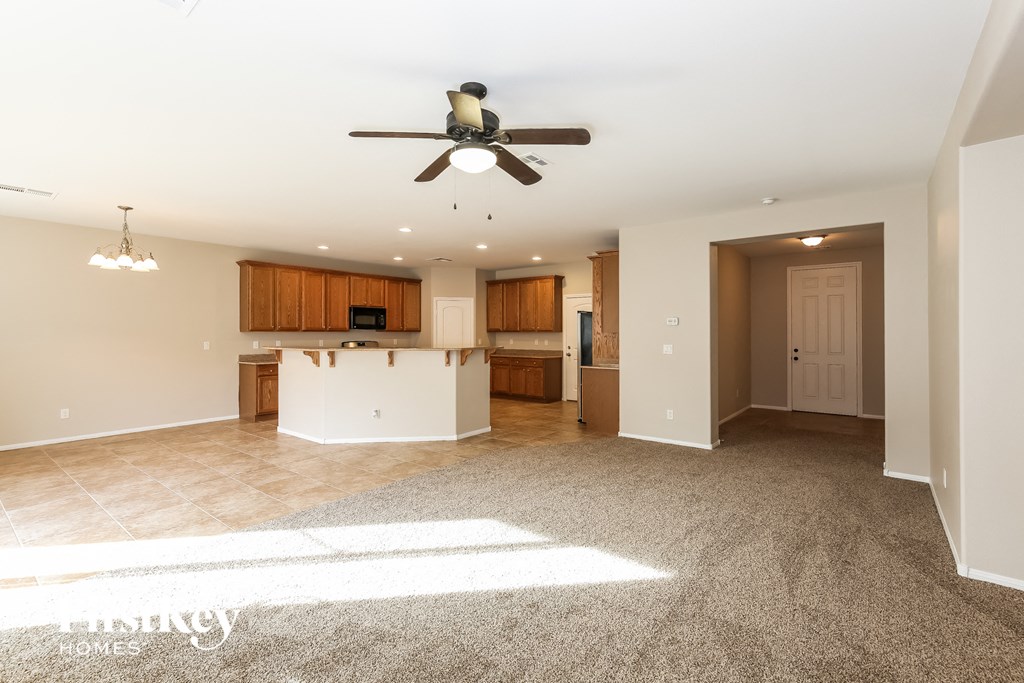 an empty living room and kitchen with a ceiling fan
