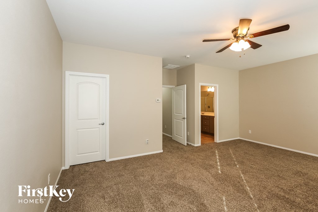 a master bedroom with carpet and a ceiling fan