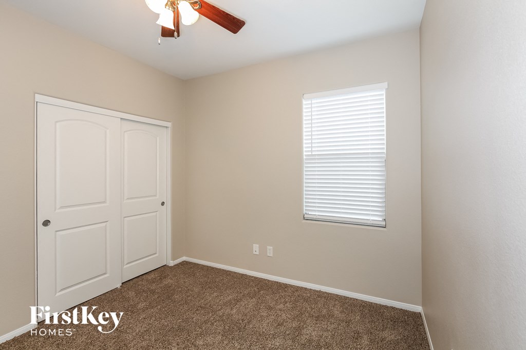 a bedroom with a carpeted floor and a door and a ceiling fan