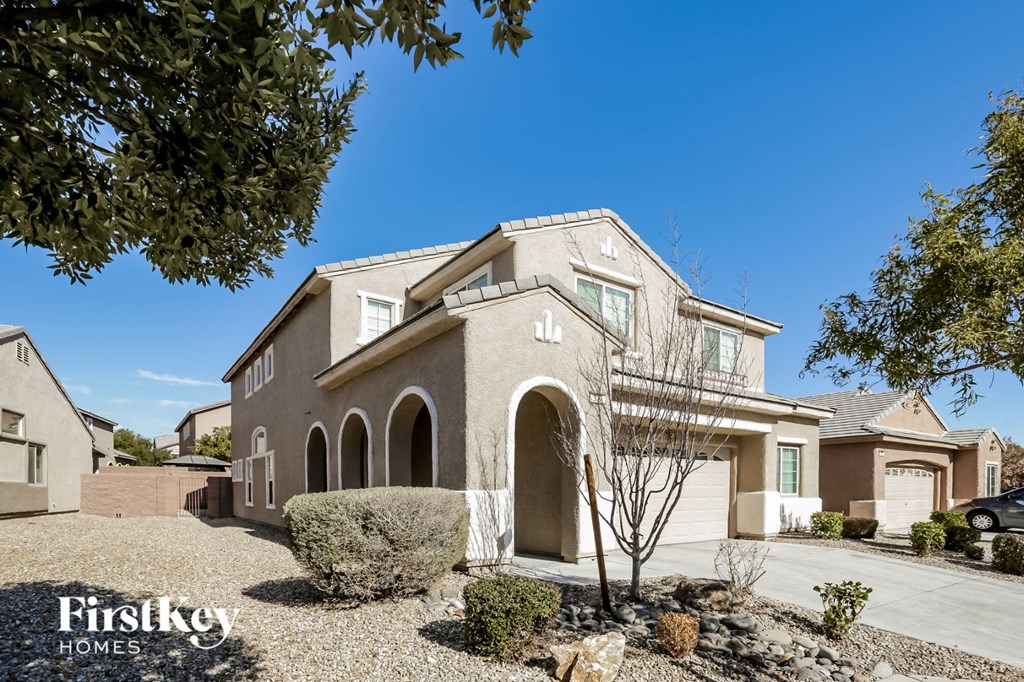 a beige brick house with a driveway and a tree