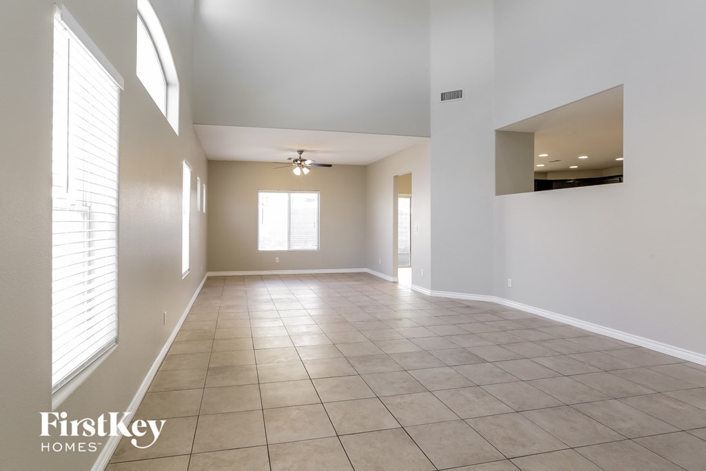 an empty living room with a ceiling fan and a window
