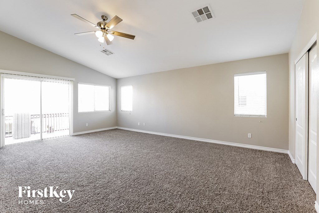 an empty living room with carpet and a ceiling fan