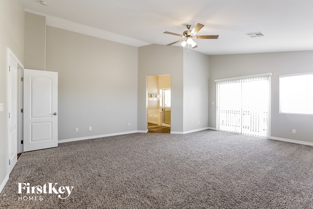 an empty living room with carpet and a ceiling fan
