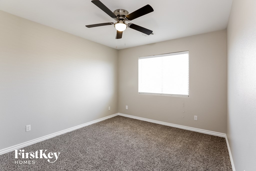 an empty room with a ceiling fan and a window
