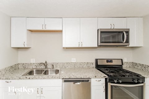 a kitchen with white cabinets and granite counter tops and a stove and microwave