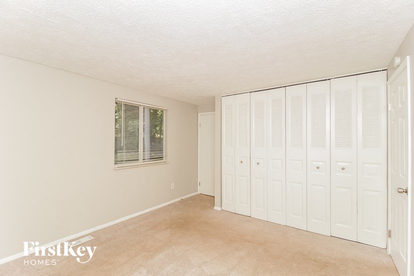 a bedroom with white closets and a carpeted floor