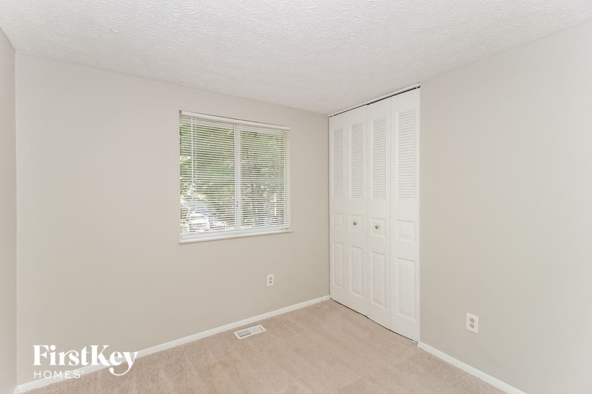 a bedroom with a door to a closet and a window