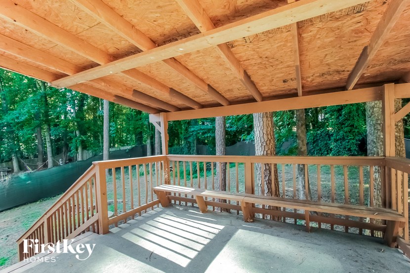 a covered porch with benches and a view of the woods
