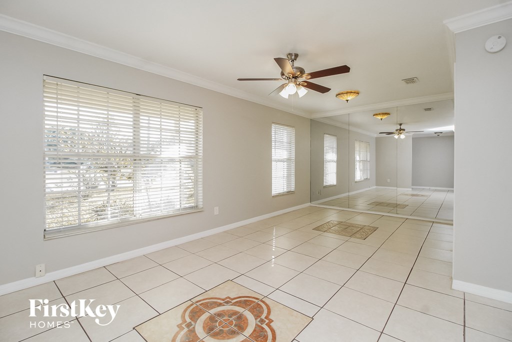 A spacious room with a ceiling fan and a rug on the floor.