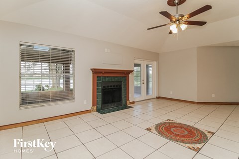 A spacious living room with a fireplace and a rug on the floor.