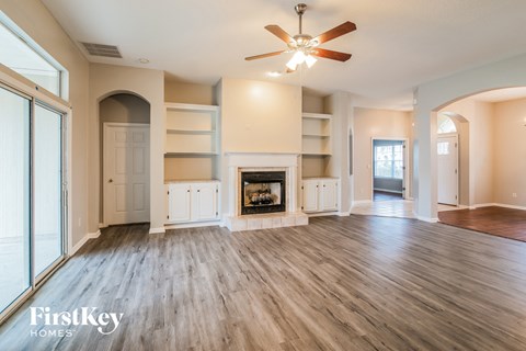 A spacious living room with a fireplace and a ceiling fan.