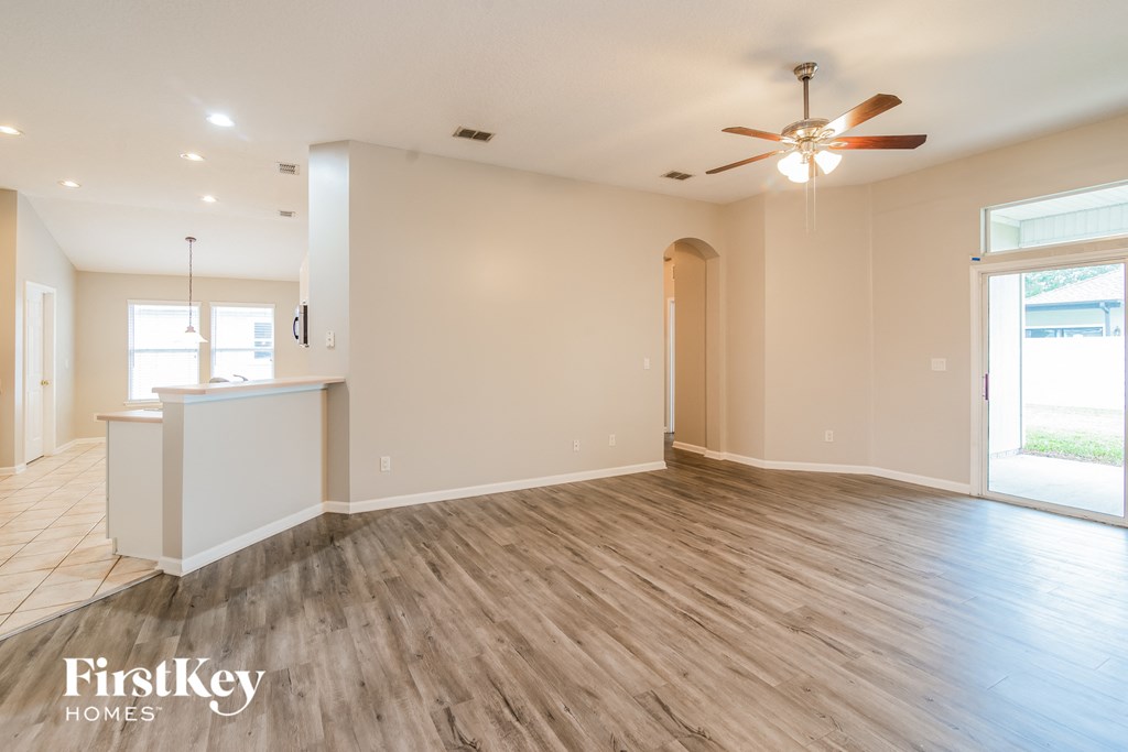 A spacious room with wooden flooring and a ceiling fan.