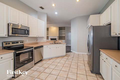 A kitchen with white cabinets and a black refrigerator.
