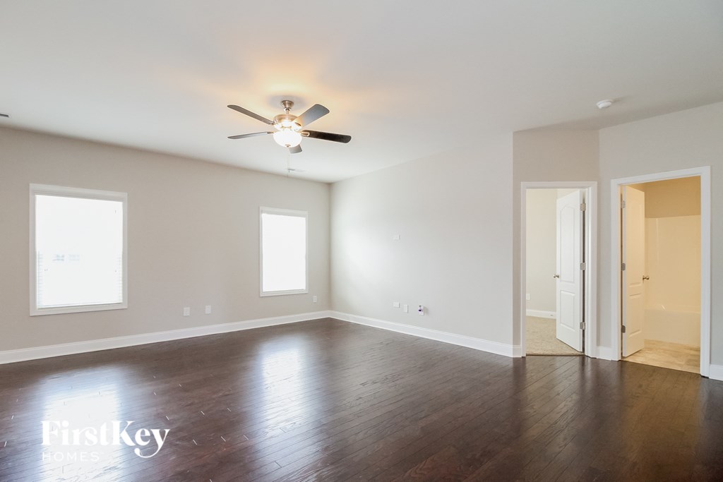 A spacious room with a ceiling fan and wooden flooring.