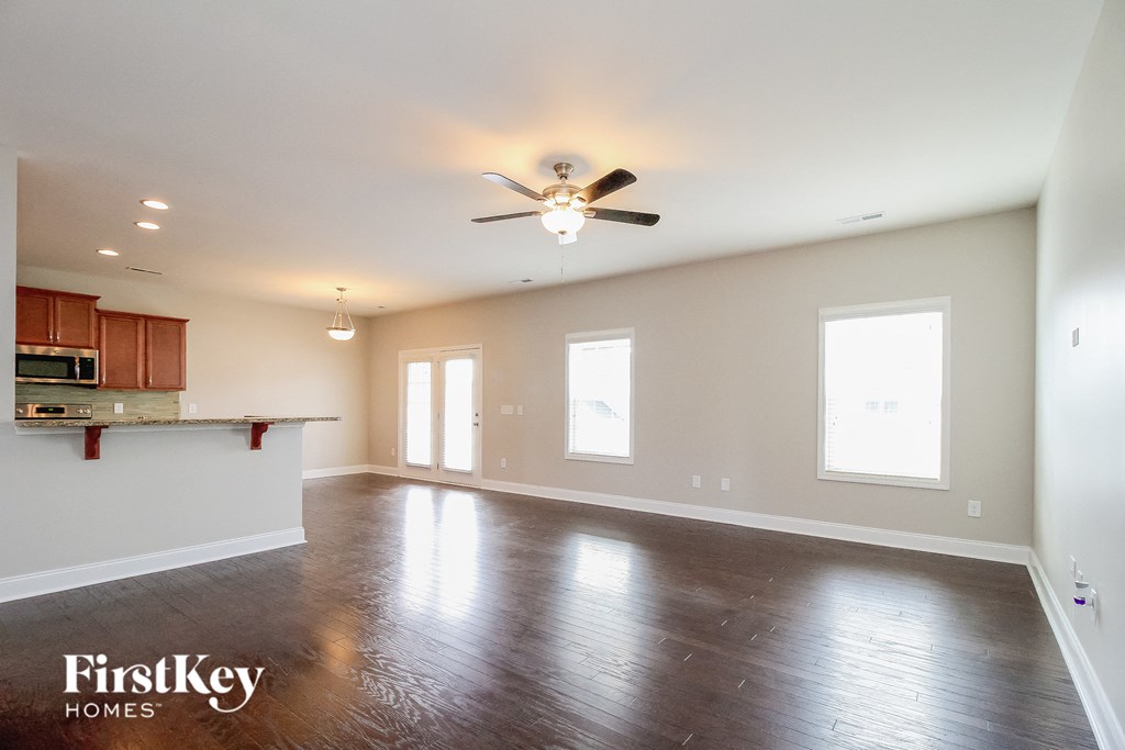 A spacious room with a ceiling fan and wooden flooring.