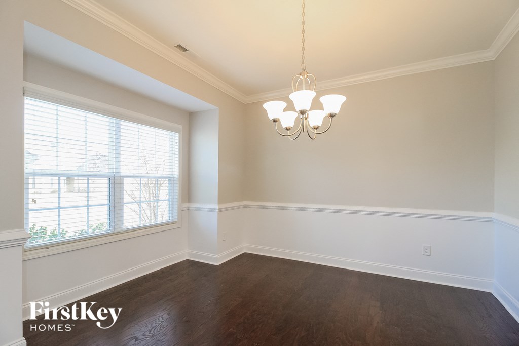 A room with wooden floors and a chandelier hanging from the ceiling.