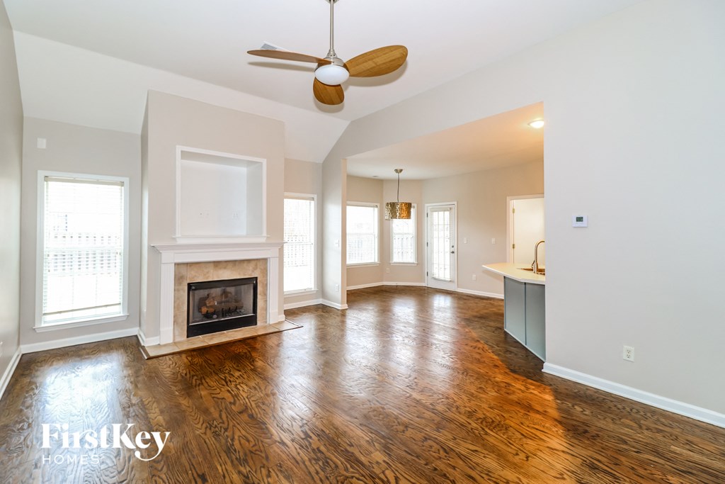 an empty living room with a fireplace and a ceiling fan