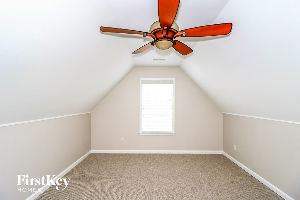 a bonus room with a ceiling fan and a window