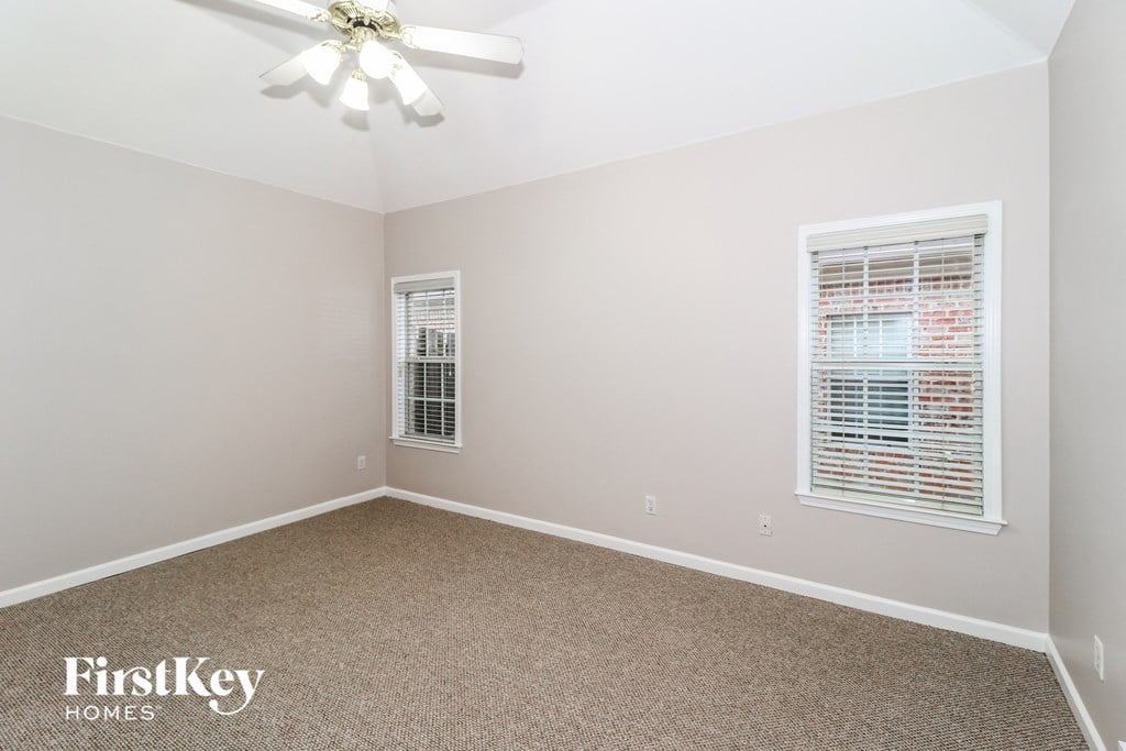 a bedroom with carpet and a ceiling fan and two windows